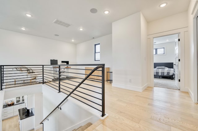 stairway featuring visible vents, wood finished floors, a healthy amount of sunlight, and recessed lighting