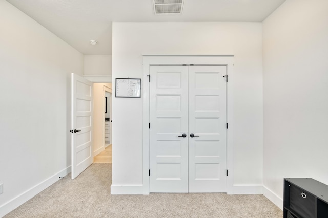 unfurnished bedroom with light colored carpet, a closet, visible vents, and baseboards