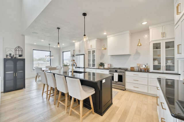 kitchen with white refrigerator, dark countertops, high end range, and light wood-style flooring