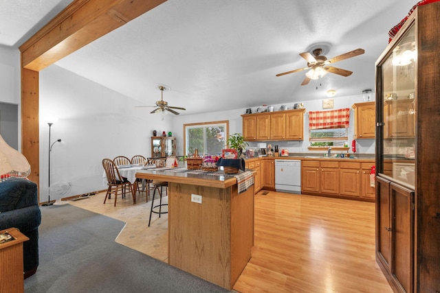 kitchen featuring white dishwasher, ceiling fan, a sink, and a breakfast bar