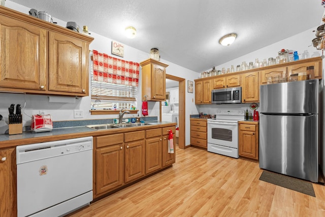 kitchen featuring a sink, brown cabinetry, stainless steel appliances, and light wood-style flooring
