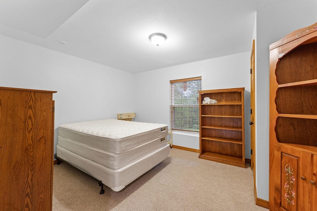 bedroom featuring light carpet and baseboards
