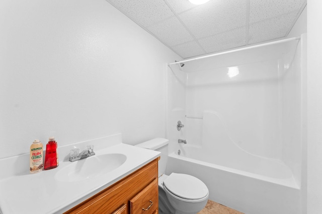 bathroom featuring bathing tub / shower combination, toilet, a drop ceiling, and vanity