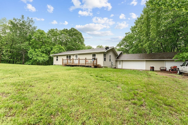 rear view of property featuring a lawn, a garage, and a wooden deck