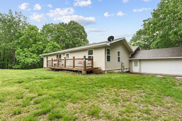 rear view of property featuring a yard, a wooden deck, and an attached garage