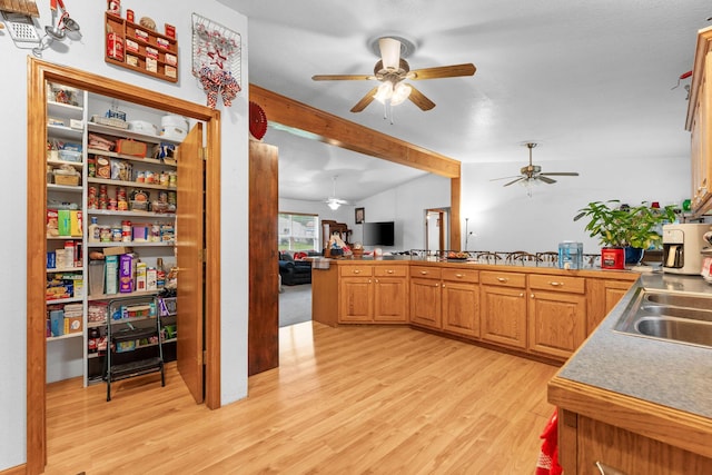 kitchen with a sink, beam ceiling, light wood-type flooring, ceiling fan, and open floor plan
