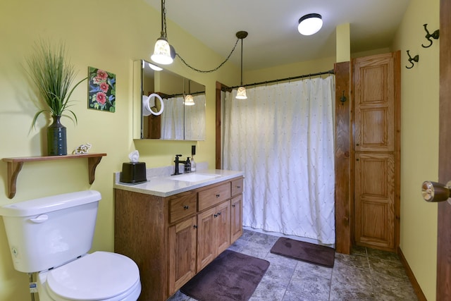 bathroom featuring vanity, toilet, a shower with curtain, and stone finish flooring