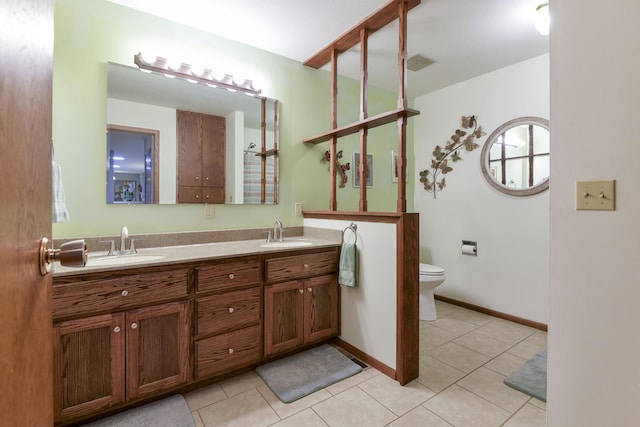 bathroom featuring toilet, tile patterned floors, double vanity, and a sink