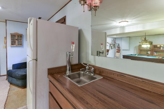 kitchen featuring freestanding refrigerator, dark countertops, pool table, and a sink