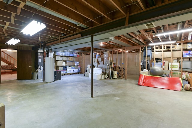 unfinished basement featuring water heater and stairway