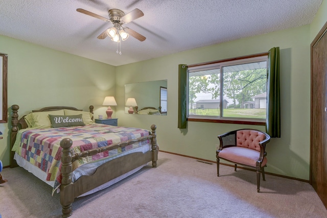 carpeted bedroom with ceiling fan, a textured ceiling, baseboards, and visible vents