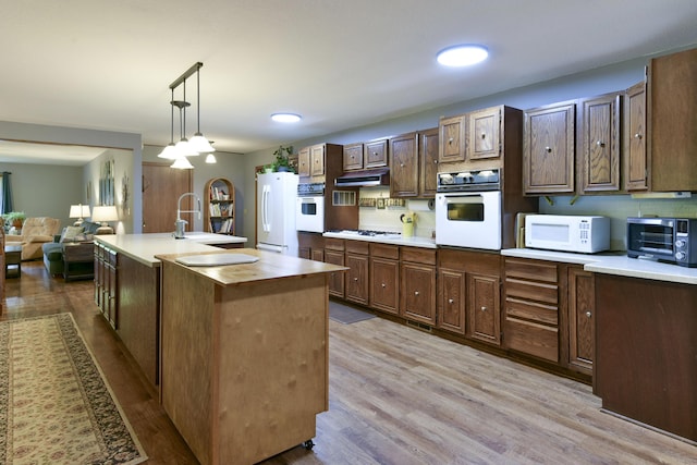 kitchen with light wood-style floors, a toaster, butcher block countertops, and white appliances