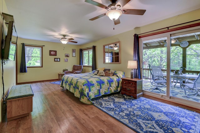 bedroom with multiple windows, wood finished floors, and access to exterior