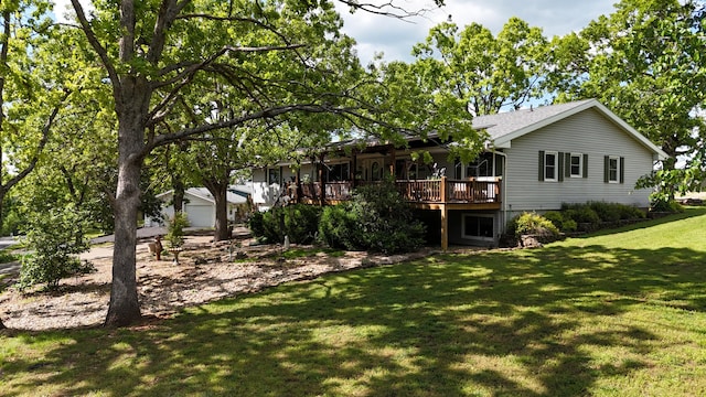 rear view of property featuring a garage, a deck, and a lawn
