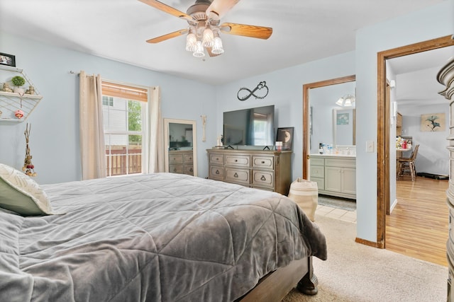 bedroom featuring light colored carpet, ensuite bath, and a ceiling fan