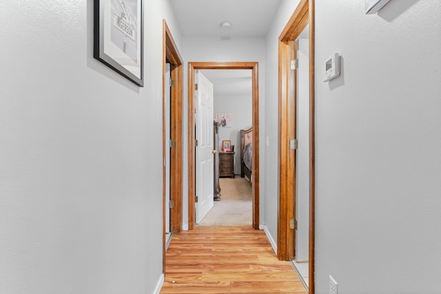 hallway featuring light wood-style flooring and baseboards