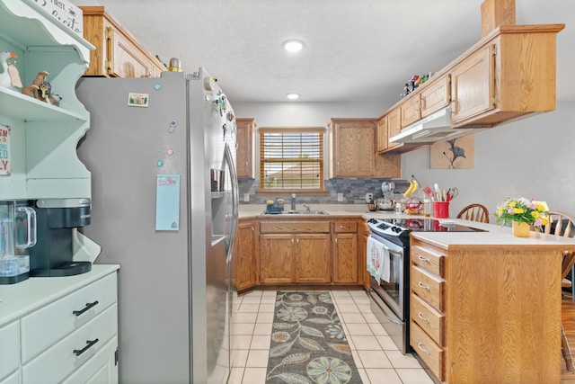 kitchen featuring a sink, a peninsula, under cabinet range hood, light countertops, and appliances with stainless steel finishes