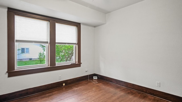 spare room with dark wood-type flooring and baseboards
