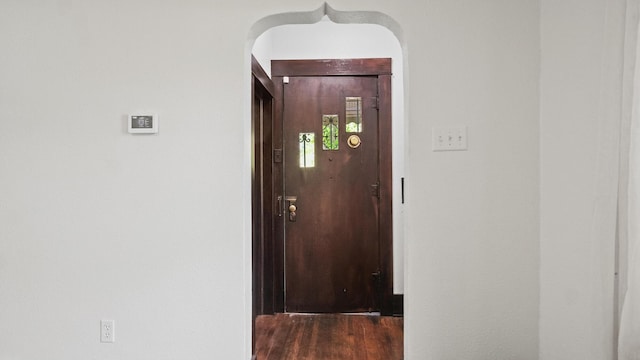hall featuring wood finished floors and arched walkways