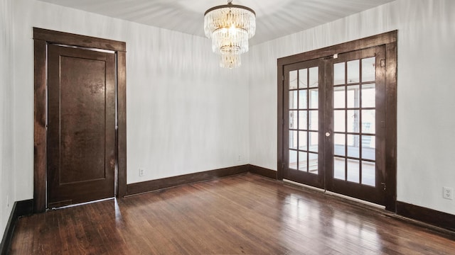 unfurnished dining area featuring a chandelier, baseboards, french doors, and wood finished floors
