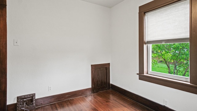 empty room featuring baseboards and dark wood-style floors