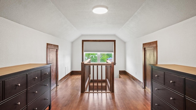 bonus room featuring a textured ceiling, vaulted ceiling, wood finished floors, and baseboards