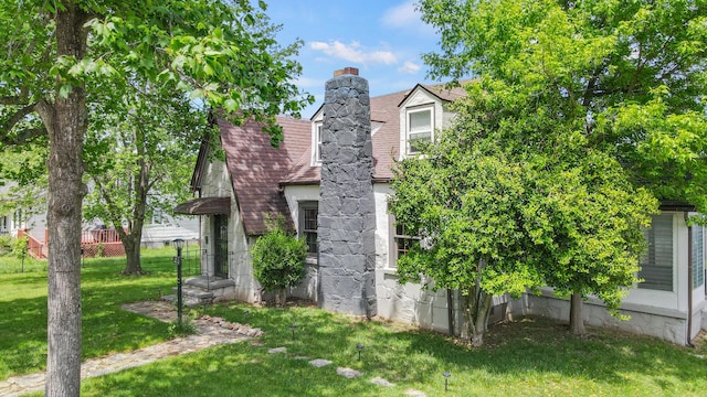 exterior space featuring a chimney and a lawn