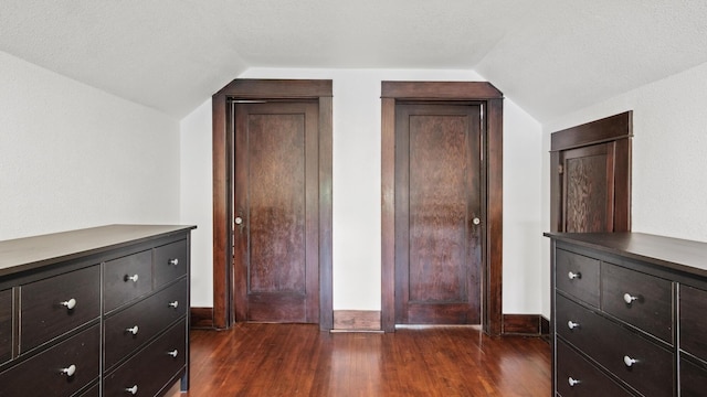 unfurnished bedroom with vaulted ceiling, baseboards, and dark wood-type flooring