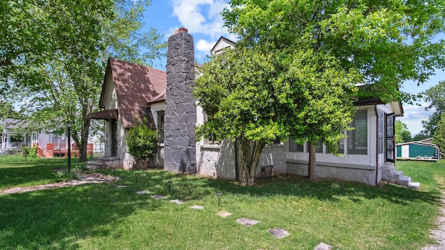 view of side of property featuring a chimney and a lawn