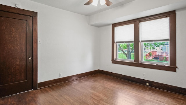 unfurnished room with baseboards, a ceiling fan, and dark wood-style floors