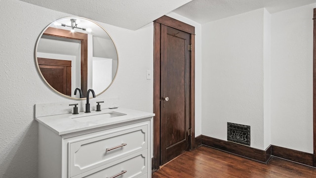 bathroom with baseboards, visible vents, vanity, wood finished floors, and a fireplace