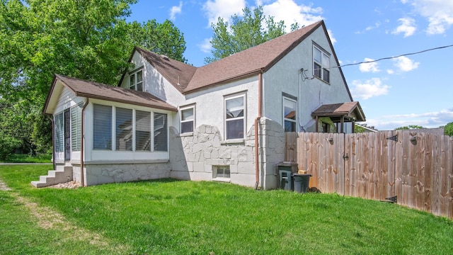 exterior space with roof with shingles, fence, stucco siding, entry steps, and a lawn