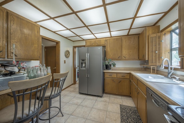 kitchen featuring light countertops, appliances with stainless steel finishes, brown cabinets, and a sink