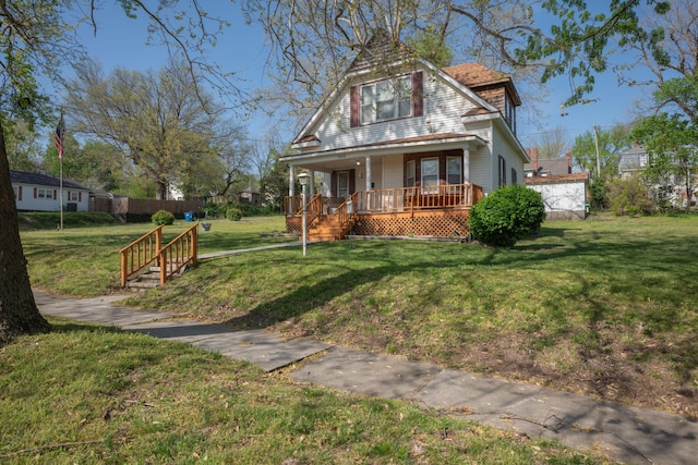 victorian-style house featuring covered porch, fence, and a front lawn
