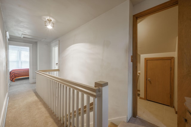 corridor featuring light carpet, an upstairs landing, and attic access