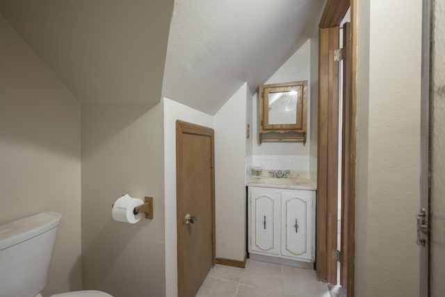 half bathroom featuring tile patterned floors, toilet, lofted ceiling, and vanity