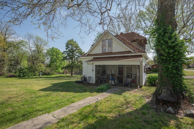 back of property with a sunroom and a yard