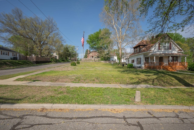view of yard featuring covered porch and fence
