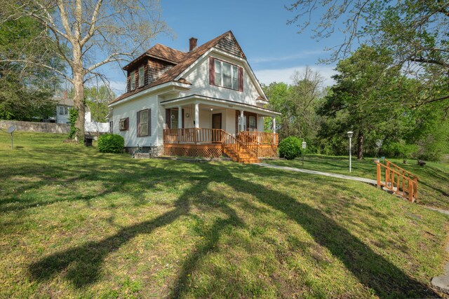 view of front of home with a porch, a chimney, and a front yard