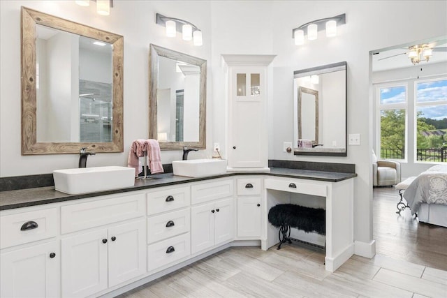 ensuite bathroom featuring double vanity, an enclosed shower, wood finished floors, and a sink