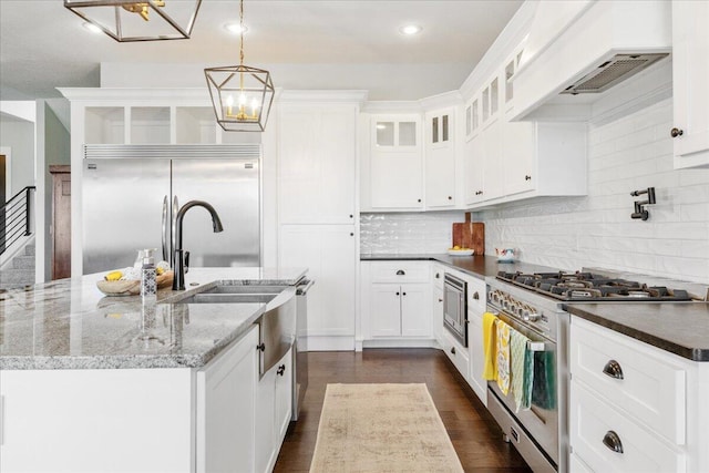 kitchen featuring glass insert cabinets, a notable chandelier, white cabinets, built in appliances, and decorative backsplash