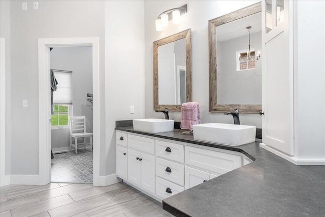 bathroom with a sink, double vanity, and baseboards