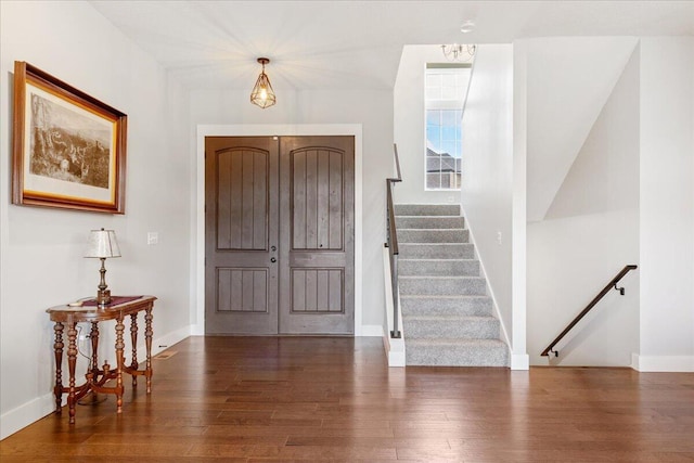 entryway featuring a chandelier, stairs, baseboards, and wood finished floors