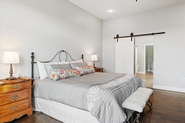 bedroom with recessed lighting, a barn door, baseboards, and wood finished floors