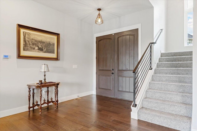 foyer entrance with baseboards, stairs, and wood finished floors