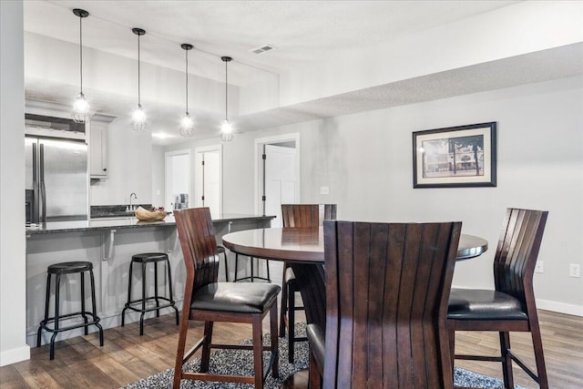 kitchen with freestanding refrigerator, a kitchen breakfast bar, and dark wood-style floors