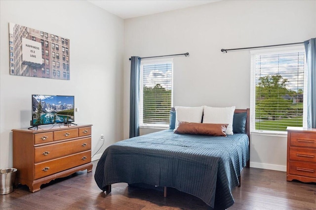 bedroom with multiple windows, dark wood-type flooring, and baseboards