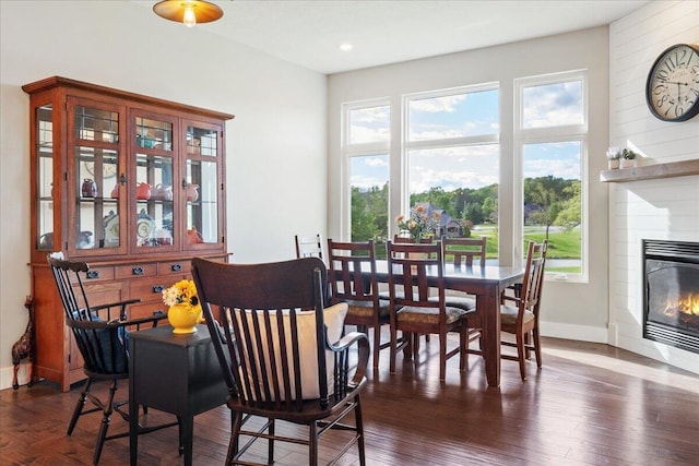 dining space featuring recessed lighting, dark wood-type flooring, baseboards, and a glass covered fireplace