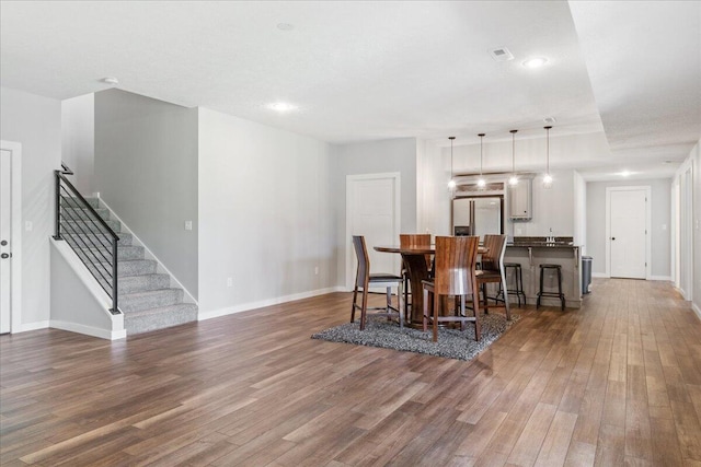 dining space featuring baseboards, stairs, visible vents, and wood finished floors