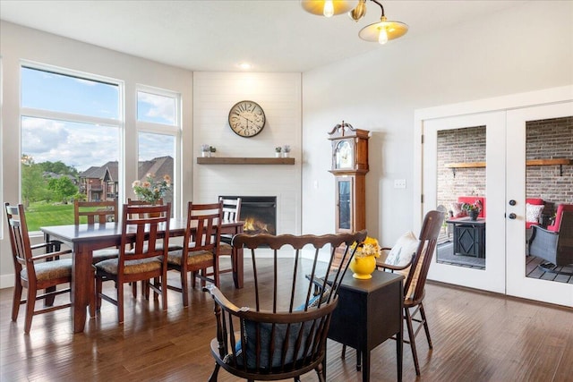 dining space with a large fireplace, dark wood-type flooring, french doors, and recessed lighting